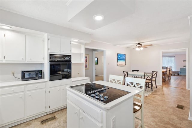 kitchen with black appliances, ceiling fan, visible vents, and a center island