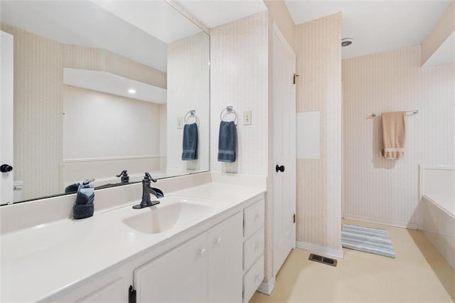 bathroom with visible vents, a bathtub, vanity, and wallpapered walls