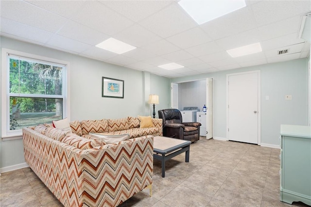 living room featuring baseboards, visible vents, a drop ceiling, and light tile patterned flooring