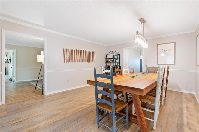 dining area with light wood-style floors, baseboards, and ornamental molding