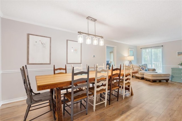 dining area with crown molding, baseboards, and light wood-style floors