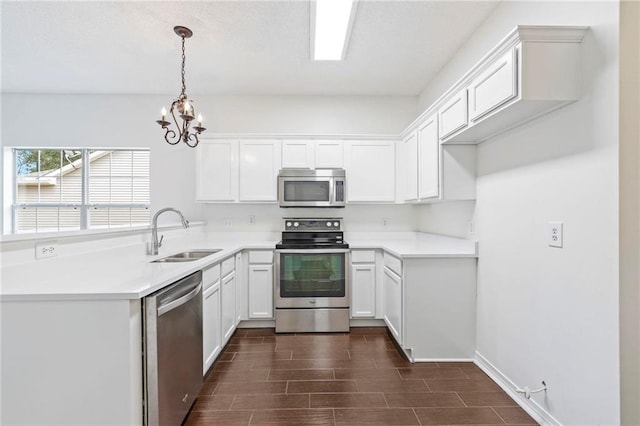 kitchen with stainless steel appliances, dark wood-type flooring, white cabinets, sink, and pendant lighting