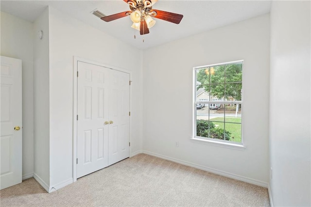 unfurnished bedroom featuring light carpet, ceiling fan, and a closet