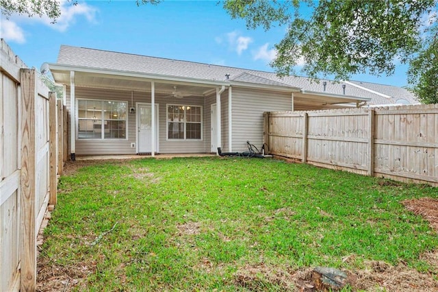 rear view of property featuring a lawn and ceiling fan