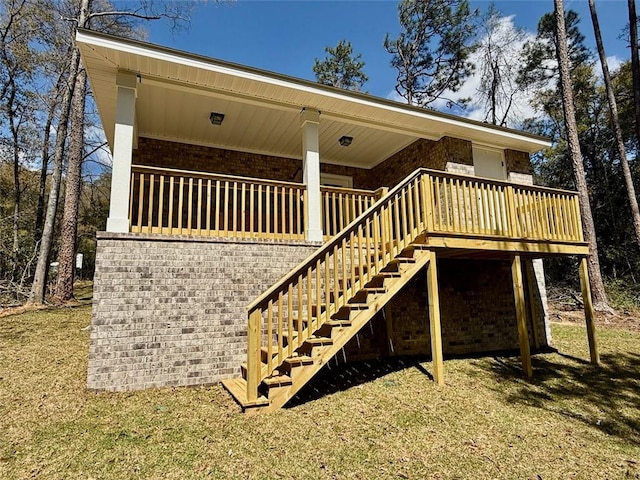 property entrance featuring a wooden deck, brick siding, and a lawn