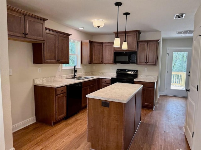 kitchen featuring black appliances, light wood-style flooring, a sink, and a wealth of natural light
