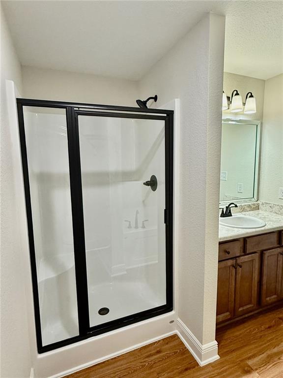 bathroom featuring a shower stall, baseboards, vanity, and wood finished floors
