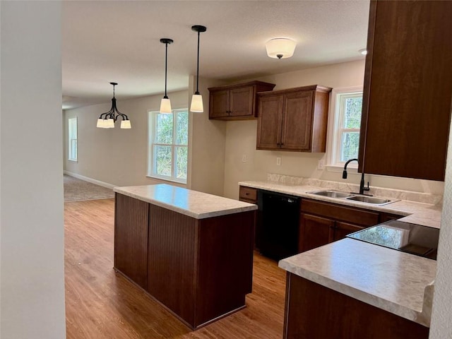 kitchen with dishwasher, a sink, a kitchen island, light countertops, and light wood-type flooring