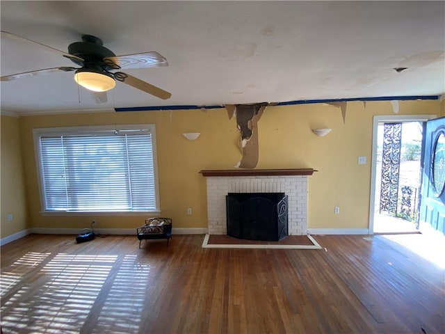 unfurnished living room featuring ceiling fan, hardwood / wood-style flooring, a fireplace, and crown molding