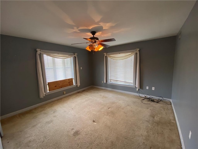 carpeted spare room featuring a wealth of natural light and ceiling fan