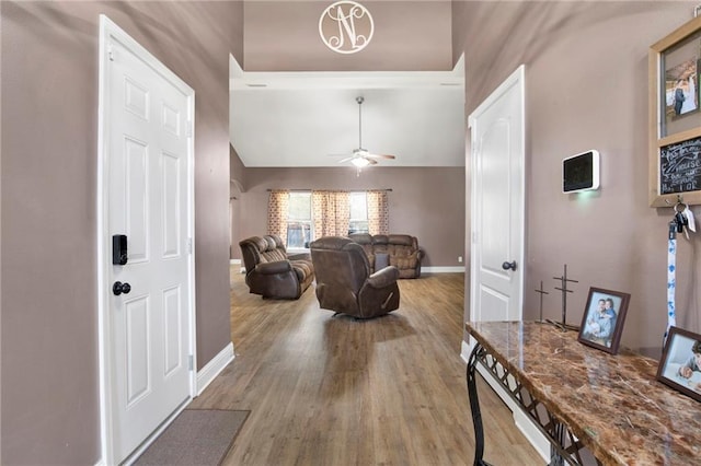 interior space featuring a ceiling fan, vaulted ceiling, wood finished floors, and baseboards