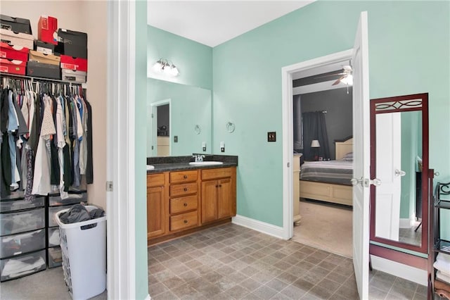 bathroom featuring ensuite bathroom, baseboards, vanity, and a ceiling fan