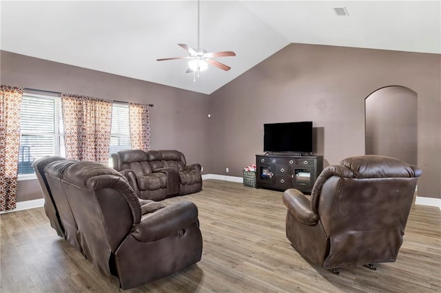 living area with visible vents, arched walkways, light wood-style floors, and ceiling fan