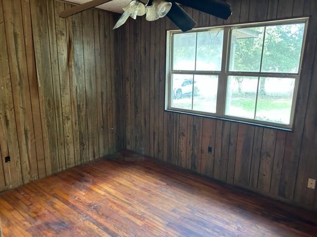 15131 Moffett Rd, Wilmer, AL 36587 - unfurnished room featuring wood walls, ceiling fan, wood finished floors, and a healthy amount of sunlight