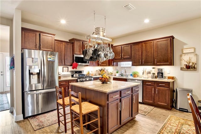 kitchen featuring a kitchen island, appliances with stainless steel finishes, a breakfast bar area, and light wood-type flooring