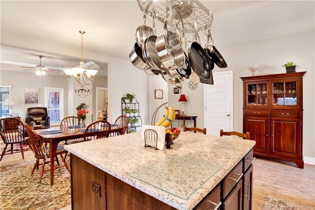 kitchen featuring decorative light fixtures, ceiling fan with notable chandelier, light hardwood / wood-style floors, and a center island