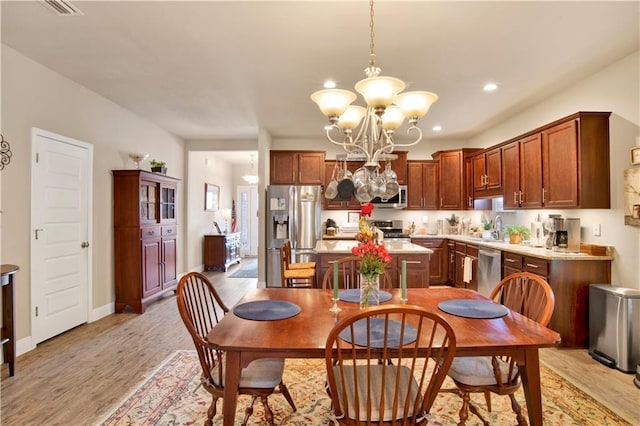 dining room featuring an inviting chandelier, sink, and light hardwood / wood-style floors