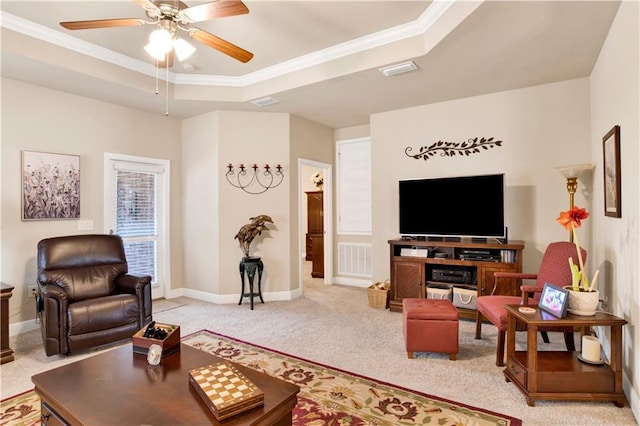 carpeted living room with ornamental molding, ceiling fan, and a tray ceiling