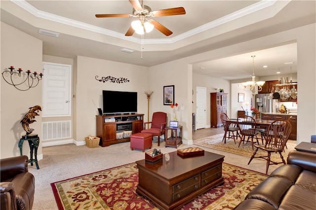 carpeted living room featuring a tray ceiling, ceiling fan with notable chandelier, and ornamental molding