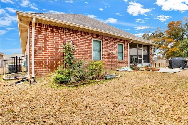 back of house featuring a sunroom, a patio, and a lawn