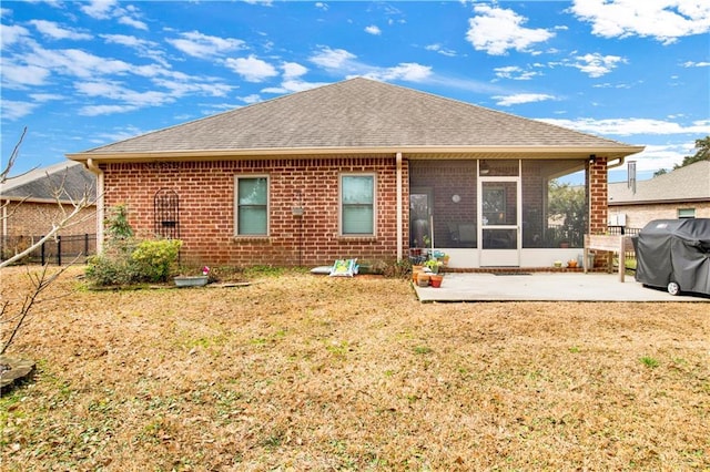 rear view of house with a sunroom, a lawn, and a patio area