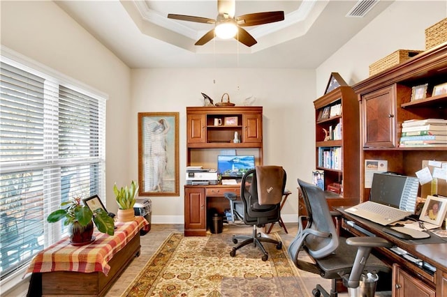 office space with crown molding, a tray ceiling, ceiling fan, and light wood-type flooring