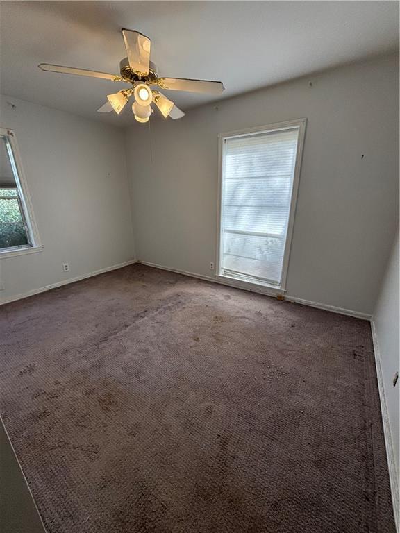 carpeted spare room featuring ceiling fan