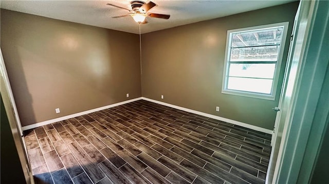 empty room with ceiling fan and dark hardwood / wood-style flooring