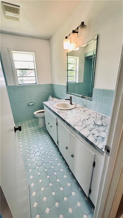 bathroom with tile walls, backsplash, vanity with extensive cabinet space, toilet, and tile flooring