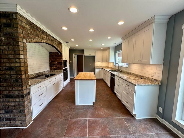 kitchen featuring sink, backsplash, white cabinetry, and a kitchen island