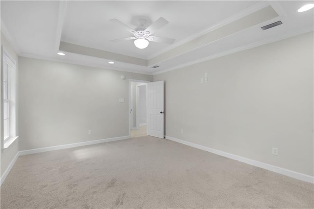 empty room with a raised ceiling, visible vents, crown molding, and baseboards