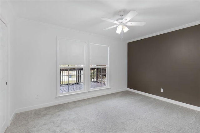 carpeted spare room with baseboards, ornamental molding, and a ceiling fan