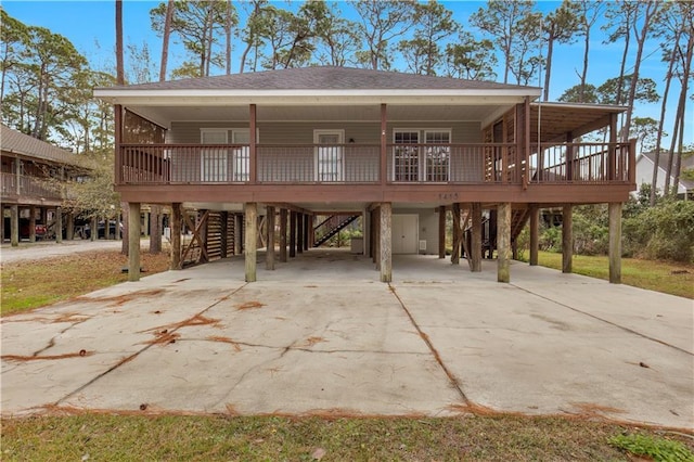 rear view of property featuring a carport, roof with shingles, a porch, and driveway