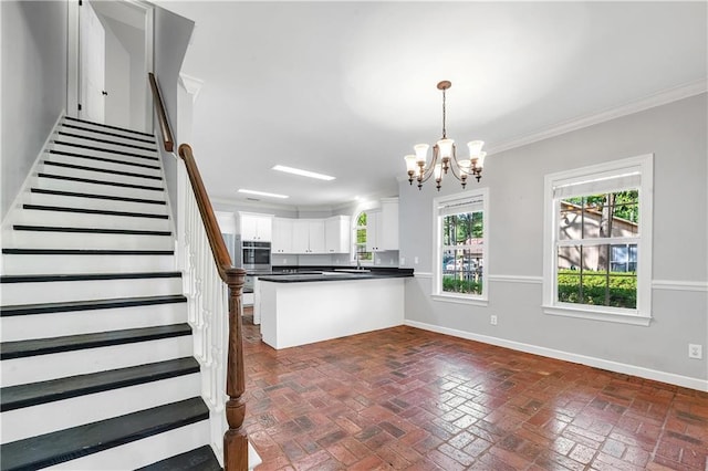 104 Ferncliff Cir, Daphne, AL 36526 - kitchen featuring brick flooring, baseboards, a peninsula, a chandelier, and crown molding