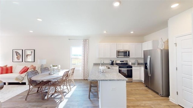 kitchen with white cabinetry, stainless steel appliances, sink, and a breakfast bar area