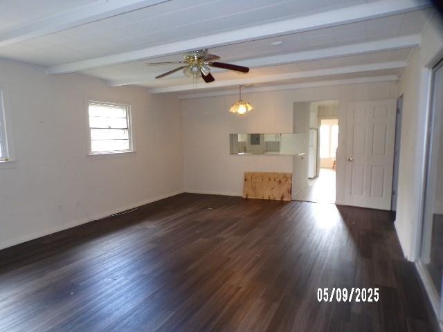 spare room with beamed ceiling, ceiling fan, dark wood-style floors, and baseboards