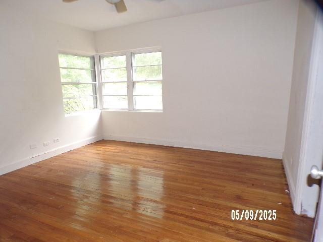 empty room with a ceiling fan, wood finished floors, and baseboards