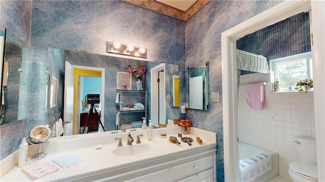 bathroom featuring a tub to relax in, vanity, tile walls, and toilet