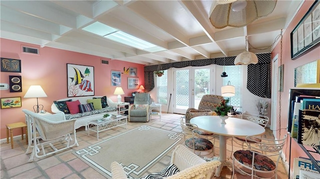 tiled living room featuring beam ceiling and french doors