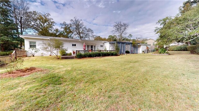 back of property featuring a wooden deck and a yard