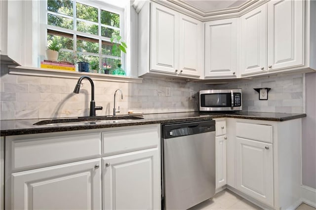 kitchen featuring white cabinets, backsplash, appliances with stainless steel finishes, and a sink