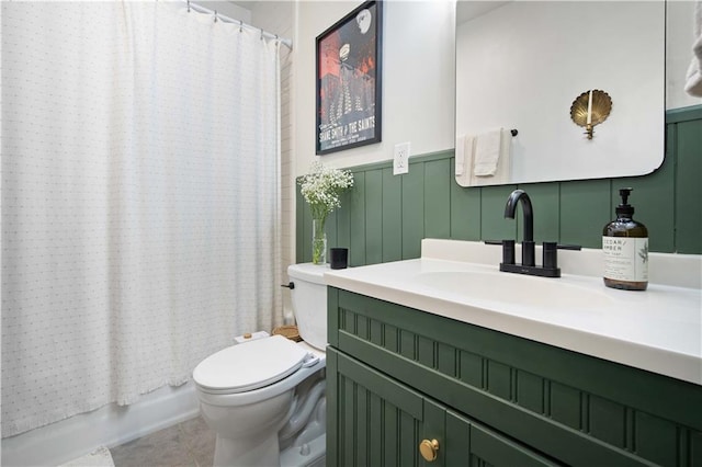 full bathroom with tile patterned flooring, shower / bath combination with curtain, toilet, vanity, and wainscoting