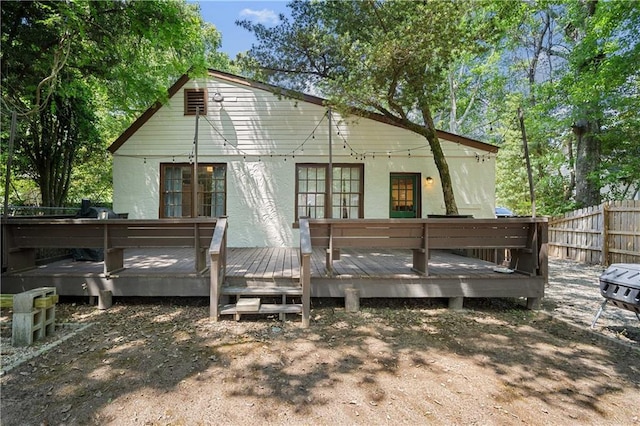 back of property with fence, a wooden deck, and stucco siding