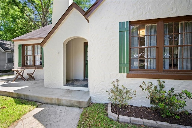 doorway to property featuring a chimney and stucco siding