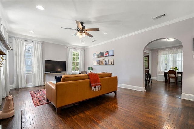 living area featuring visible vents, arched walkways, dark wood-type flooring, and ceiling fan