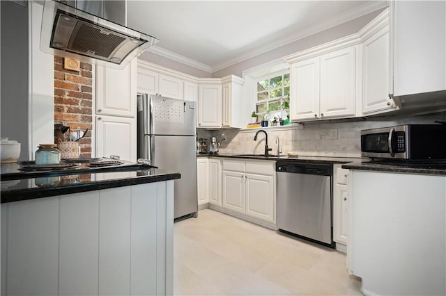 kitchen with exhaust hood, dark countertops, a sink, appliances with stainless steel finishes, and white cabinetry