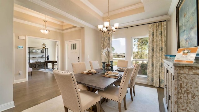 dining area featuring a tray ceiling, a notable chandelier, crown molding, and dark hardwood / wood-style flooring