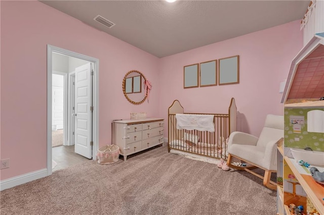 carpeted bedroom featuring baseboards, visible vents, and a crib