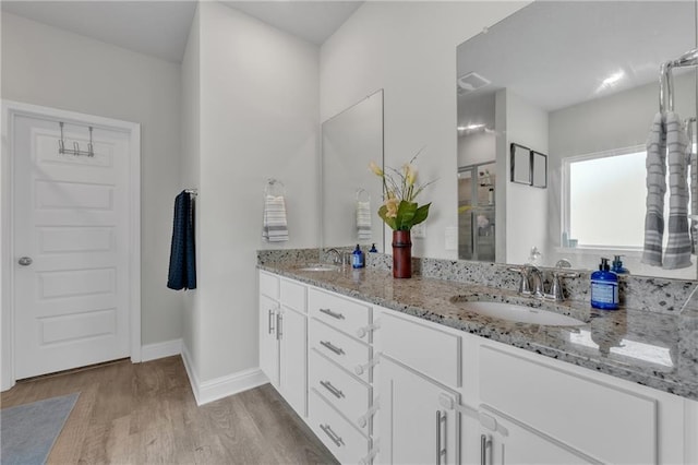 bathroom with double vanity, visible vents, a sink, and wood finished floors