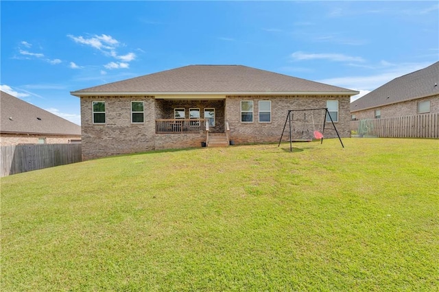 back of property with a yard, a playground, brick siding, and a fenced backyard